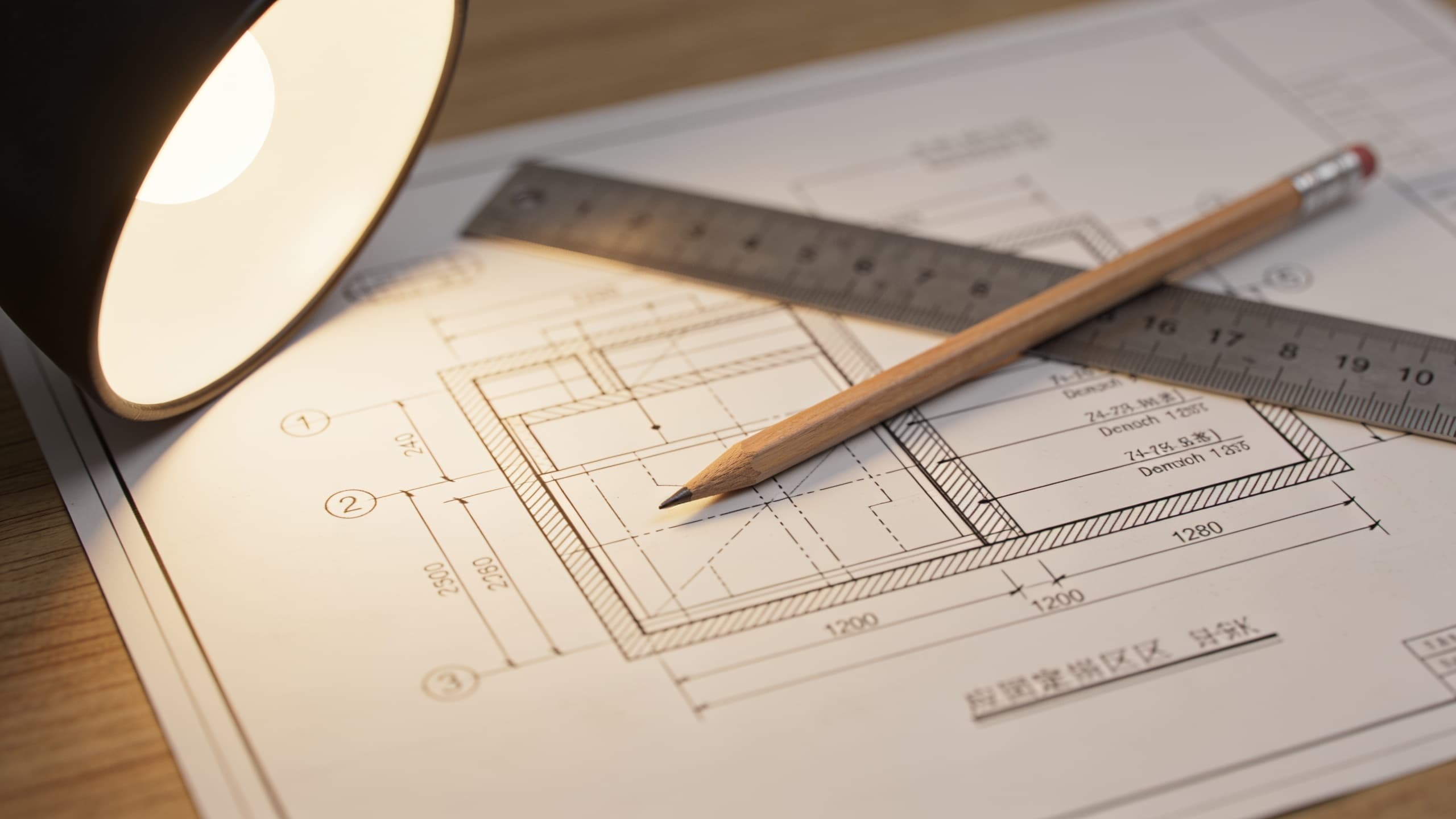 Close up of a construction drawing sheet with a wall section detail, pencil and scale rule resting on it